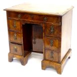 A mid 18thC walnut kneehole desk, the feather banded top with a moulded cornice above frieze