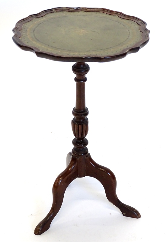 A mahogany wine table, the circular dished top with a shaped edge and green leather inset, on turned