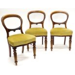 A set of three Victorian mahogany balloon back chairs, each with a serpentine shaped padded seat, on