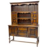 A 1920's oak dresser, the raised back with a moulded cornice, shaped apron and arrangement of two