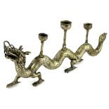 An eastern silver coloured metal candlestick, cast in the form of a dragon, with three branches