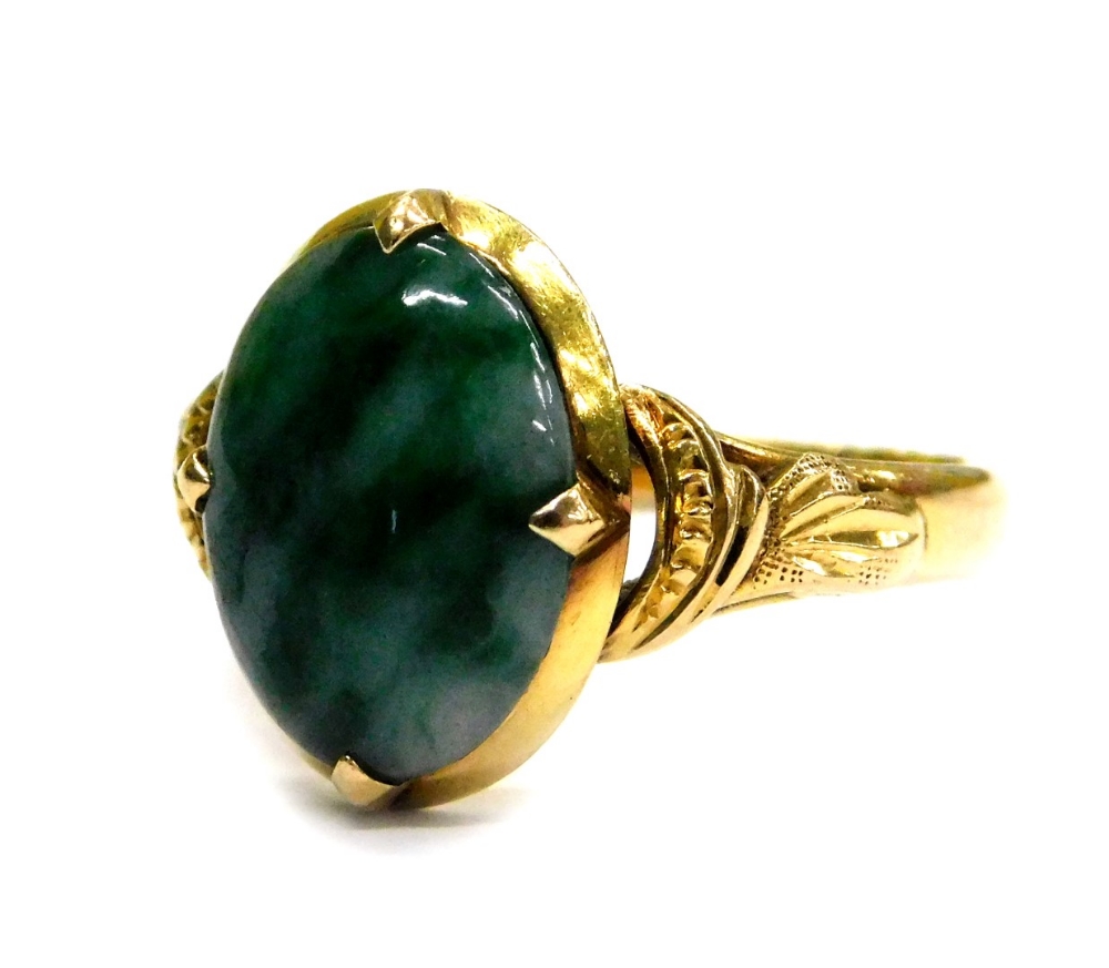 A modern jade set dress ring, the oval jade with pale and dark green striations, in a four claw