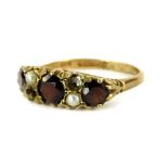 A 9ct gold gypsy ring, set with three garnet and seed pearls (two missing), in scroll design