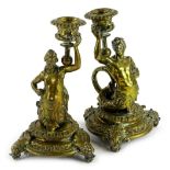 A pair of late 19thC continental gilt brass candlesticks, each modelled in the form of a male and