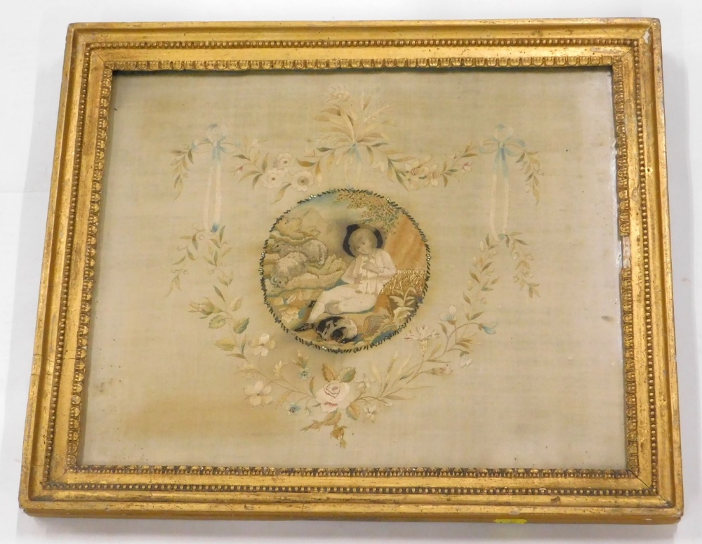 An early 19thC silk embroidered picture, decorated centrally with a young boy, sheep, etc.,