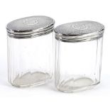A pair of Victorian facetted oval cut glass dressing table jars, each with an engine turned lid with