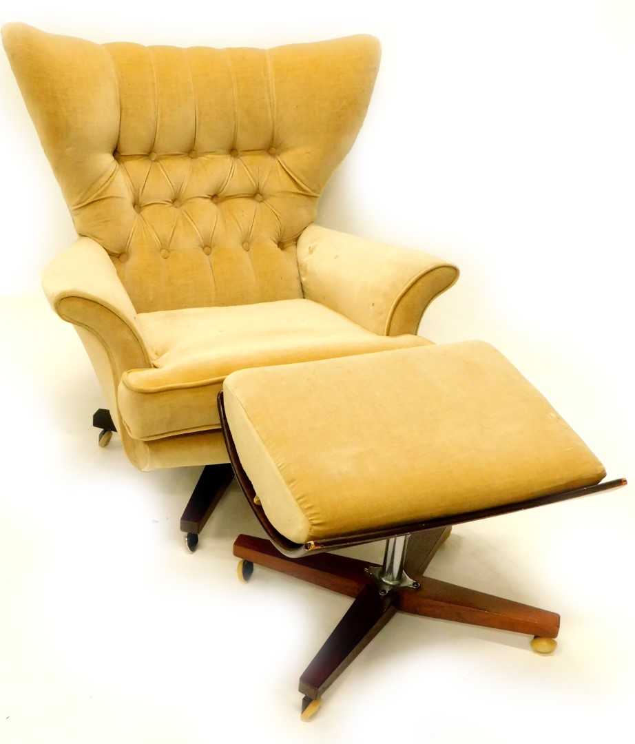 A 1960's G Plan type revolving wing armchair, with buttoned upholstery on 'X' shaped rosewood base