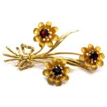 A triple flower brooch, in a triple length spray, each set with garnet, approx 5mm diameter, each