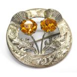 A silver plated thistle brooch, set with two orange coloured costume stones, 4cm wide.