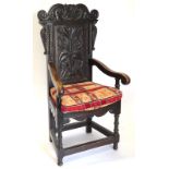 A 19thC and earlier oak Wainscot chair, the panelled back carved with leaves, flowers, scrolls, etc,