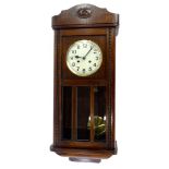 A 1920s oak wall clock, the dial with Arabic numerals, flanked by beaded sides, 77cm high.