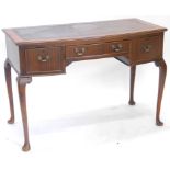 A mid-20thC mahogany bow fronted writing table, the top with a brown leather inset, above three