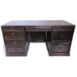 An oriental hardwood kneehole desk, with an arrangement of drawers and slides etc, on a plinth base,