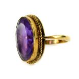 A 9ct gold dress ring, set with oval faceted amethyst stone, in rub over gold setting, with rope