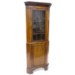 A walnut standing corner cabinet in mid-18thC style, the top of the cabinet with a glazed door and