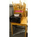 A pine kitchen table, four chairs, a De Longhi microwave, and a clothes airer.