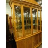 A lightwood breakfront display cabinet, and a matched extending dining table.