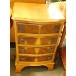 A small yew wood serpentine side cabinet, of four drawers terminating in ogee bracket feet.