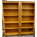 A pair of open bookcases, each with carved decoration.