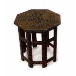 An Indian hardwood folding occasional table, the octagonal top carved with scrolling leaves and