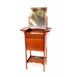 An Edwardian mahogany shaving stand, the swing frame mirror raised on two shelves, above a frieze