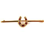 A ruby and diamond nine stone horseshoe bar brooch, set in yellow metal stamped 9ct, 4.3g.