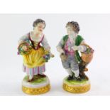 A pair of 20thC Volkstedt porcelain figures, of a boy with grapes and a girl with flowers, raised on