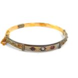 A 15ct gold bangle set, with a diamond flanked by a pair of spinnels, safety chain as fitted, 8.2g.