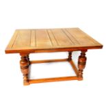 A 17thC style oak draw leaf dining table, raised on cup and cover supports, united by a box
