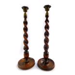 A pair of 1930's barleytwist tapering oak candlesticks, with gilt brass sconces, 47cm high.