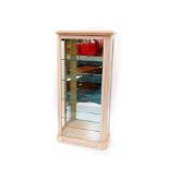 A limed oak display cabinet, with an outswept pediment, above a glazed door, opening to reveal a