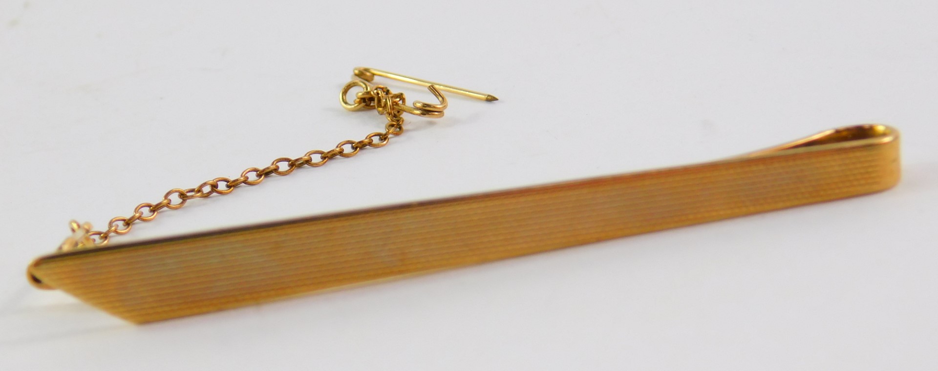 A 9ct gold tie slide, with engine turned decoration and safety pin as fitted, 6.2g.
