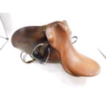 A tan leather riding saddle, with stirrups, and bridle straps. (a quantity)