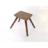A 19thC elm and oak milking stool, the rectangular top raised on four turned splayed circular