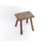 A 19thC elm milking stool, the rectangular top raised on four turned legs, 28cm wide, 19.5cm deep,