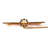 An Edwardian sapphire and seed pearl bar brooch, in a circular setting, in yellow metal stamped 15c,