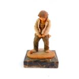 A resin sculpture of a boy relieving himself, signed indistinctly, raised on a rectangular veined