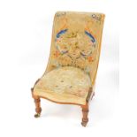 A Victorian rosewood nursing chair, upholstered in floral tapestry, raised on turned and lappet