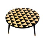 A 1950's circular ebonised coffee table, with a gold and black spotted triangular inlaid circular
