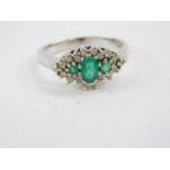An 18ct white gold emerald and diamond cluster ring, claw set, size P, 5.0g.