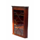 A Georgian mahogany wall hanging corner cupboard, with an outswept pediment, above a glazed door,
