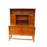 A 17thC style oak dresser, the two shelf plate rack with outswept pediment and a pair of panelled