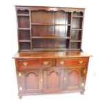 An 18thC oak dresser, the plate rack with later apron, over three shelves flanked by eight recesses,