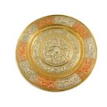 An Indian brass and damascene circular dish, embossed with a Hindu deity surrounded by panels of