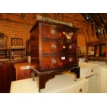 A reproduction mahogany serpentine chest of three drawers, raised on bracket feet terminating on