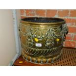 A brass log bucket, with lion head handles and embossed decoration, 31cm high, 42cm diameter.