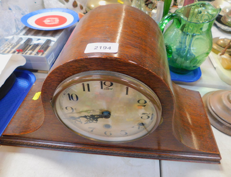 An early 20thC oak cased mantel clock, the silver dial bearing Arabic numerals, eight day movement