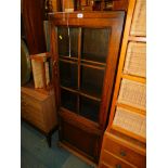 A narrow oak bookcase, enclosing two adjustable shelves, with a glazed upper section and a lower