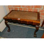 An early 20thC walnut stool, with caned seat above a carved apron raised on ball and claw feet, 39cm