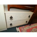 A Maple & Co low chest, of two drawers with carved fronts, and large ornate drop handles, painted